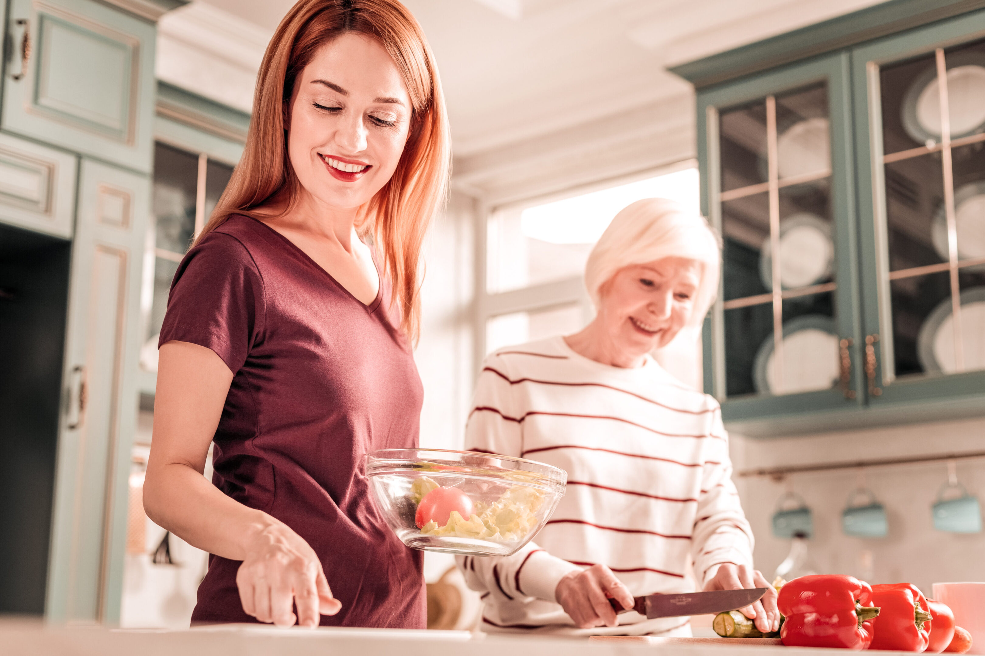 Love cooking. Pleased girl keeping smile on her face while preparing dinner