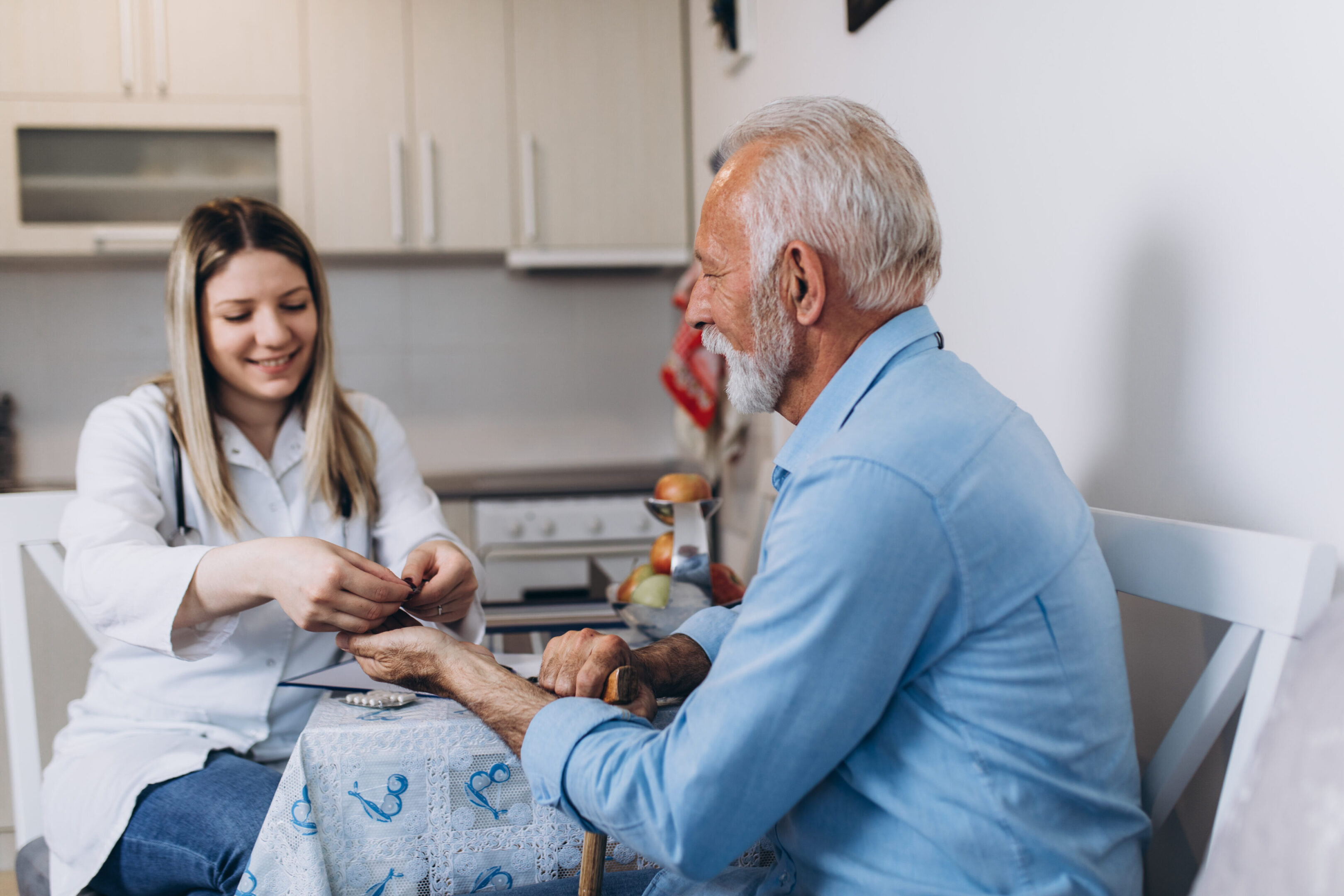 Young positive caregiver taking care of senior man in nursing home